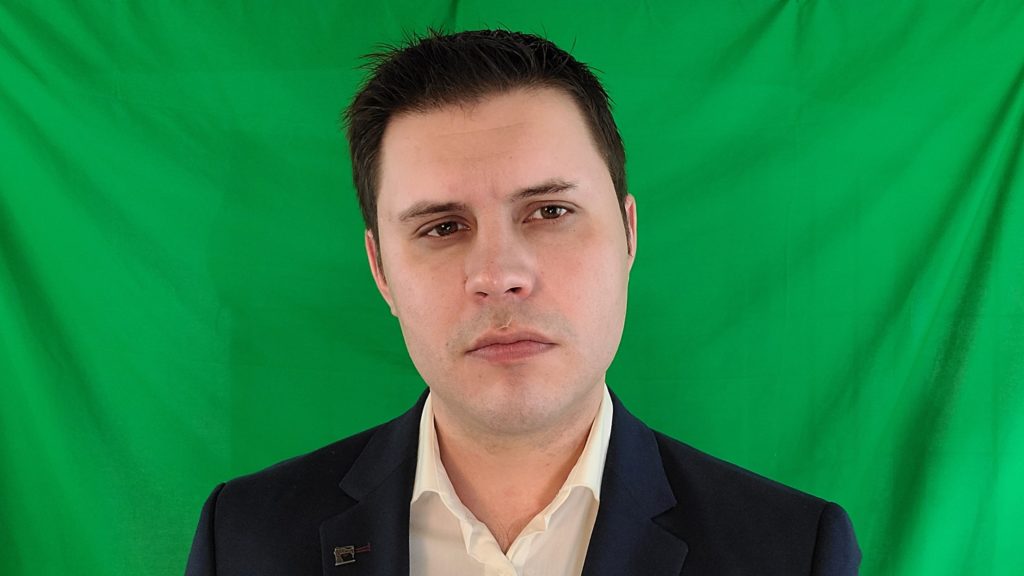 Mark Slapinski stands in front of a green screen